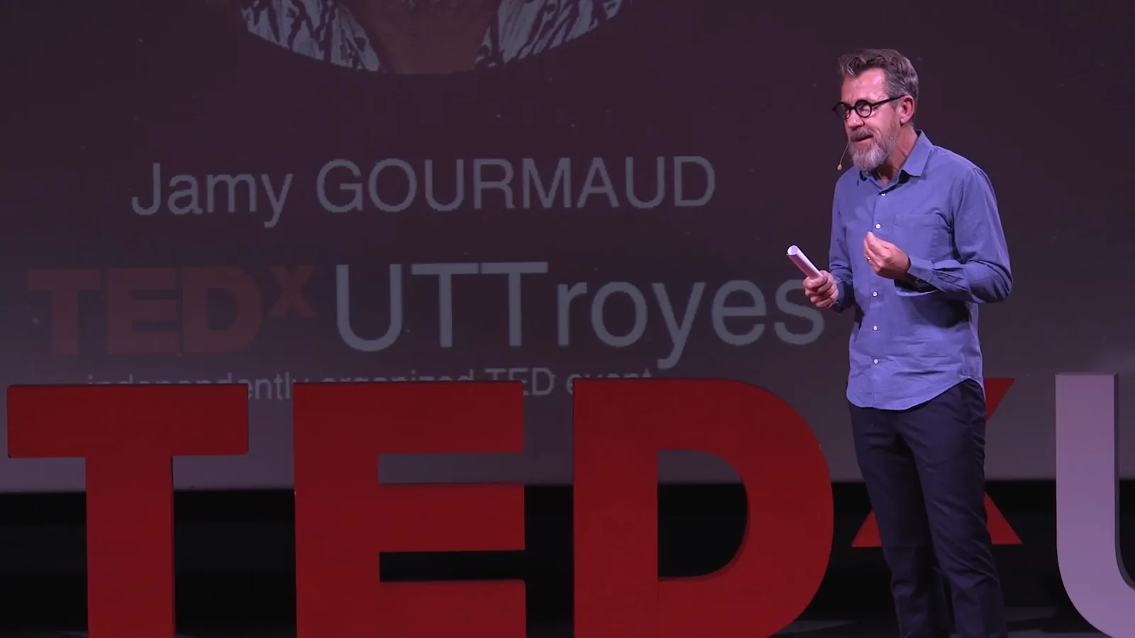 Jamy Gourmaud sur la scène de TEDxUTTroyes, devant les lettres rouges
